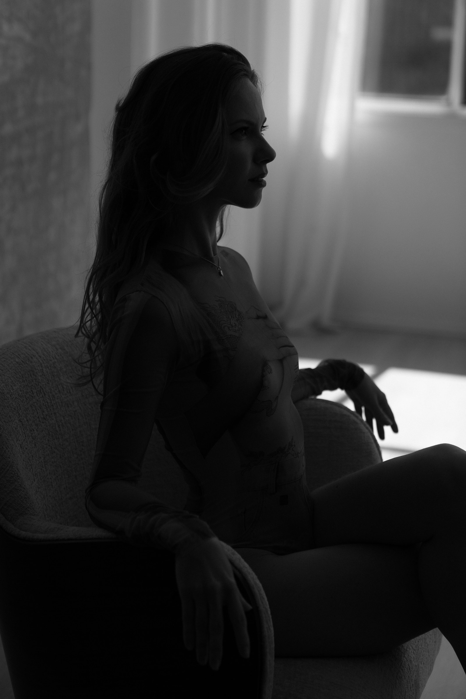 Black and white silhouette of Nata sitting in a chair by a window